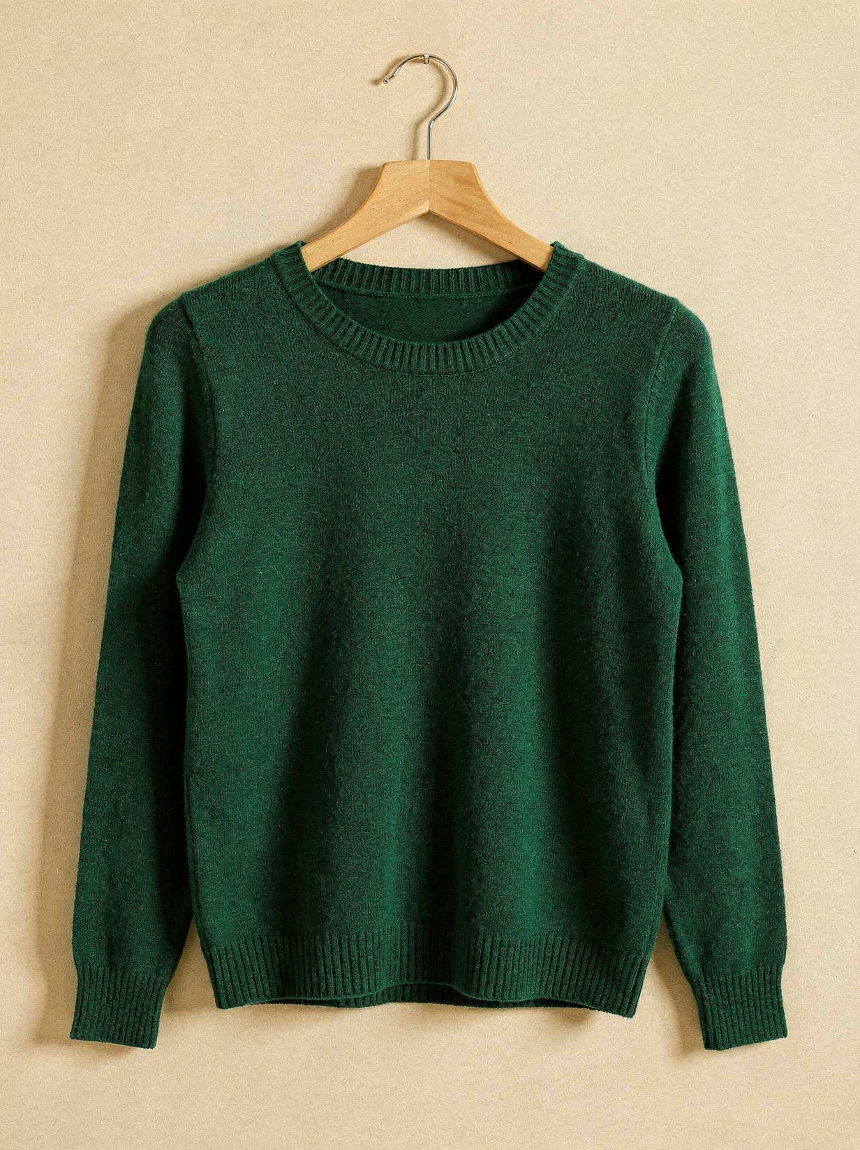 Bottle green merino wool crew neck jumper on a wooden hanger