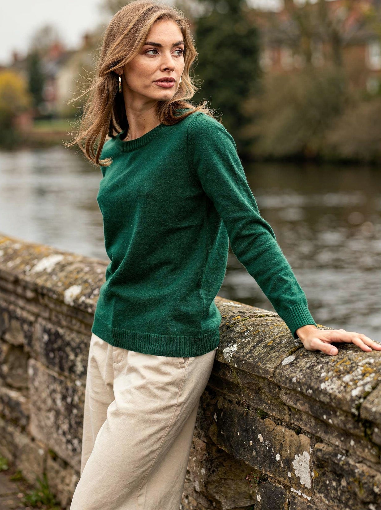 Bottle green merino wool crew neck jumper worn on a stone bridge