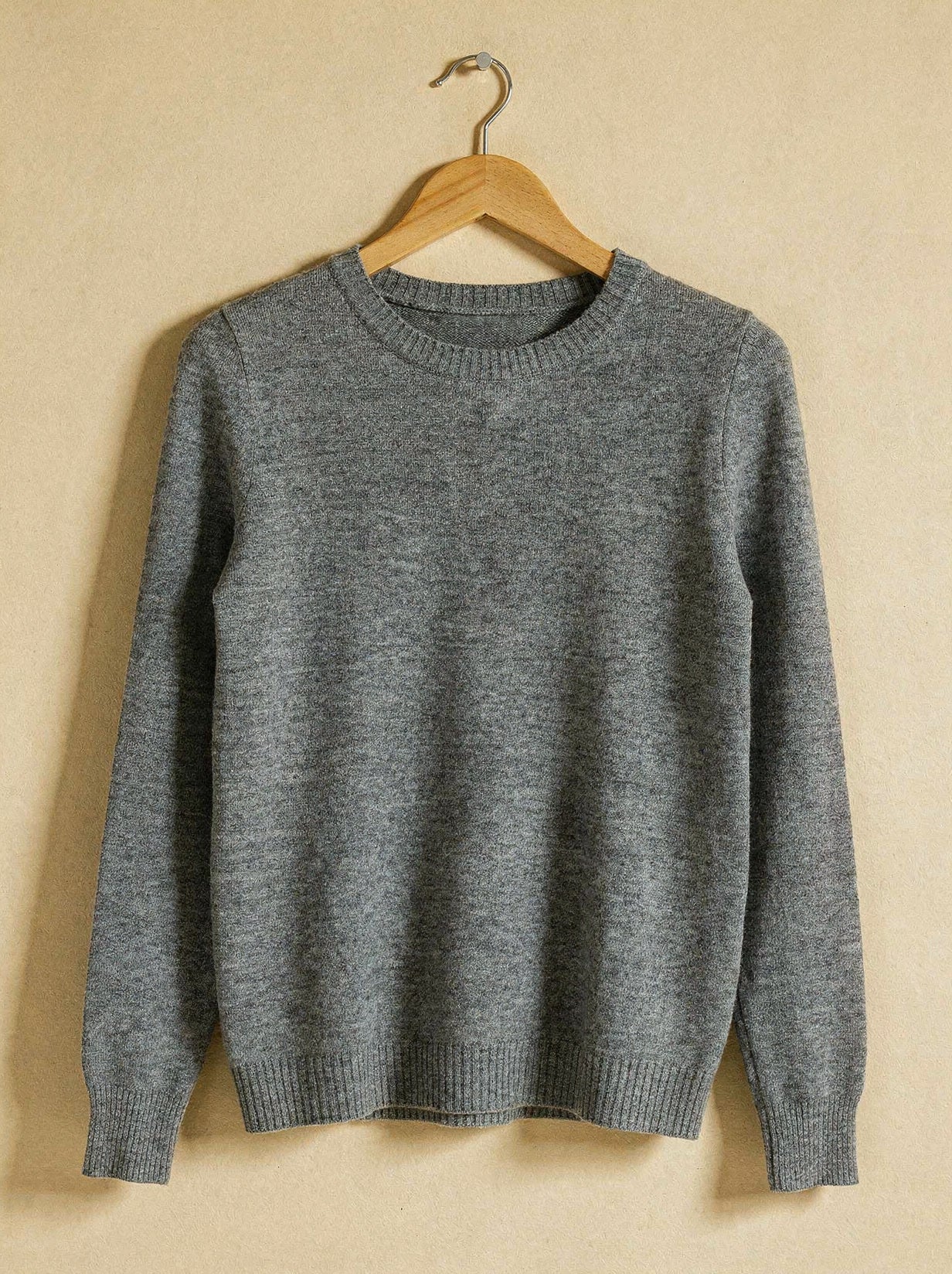 Grey marl merino wool crew neck jumper on a wooden hanger