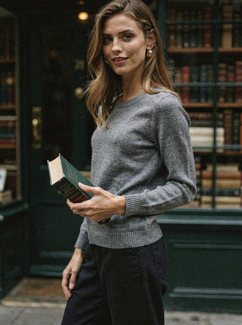 Woman wearing a grey marl 100% merino wool crew neck jumper outside a bookshop
