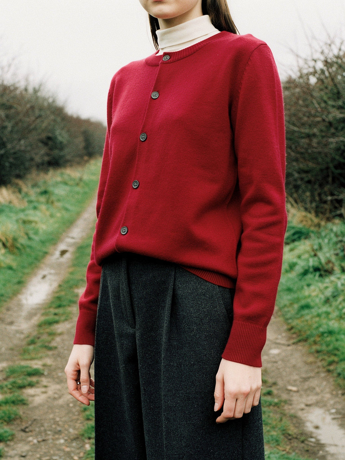Merino wool cardigan in Cranberry, worn buttoned on an English green lane