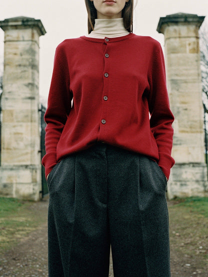 Merino wool cardigan in Cranberry, worn beside a pair of stone gate piers