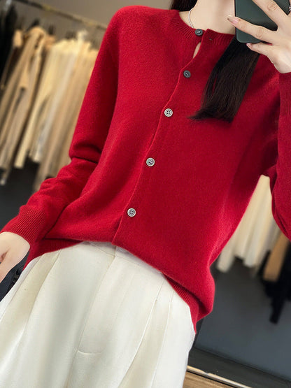 The Hawling merino wool cardigan in Cranberry, worn with wide white trousers