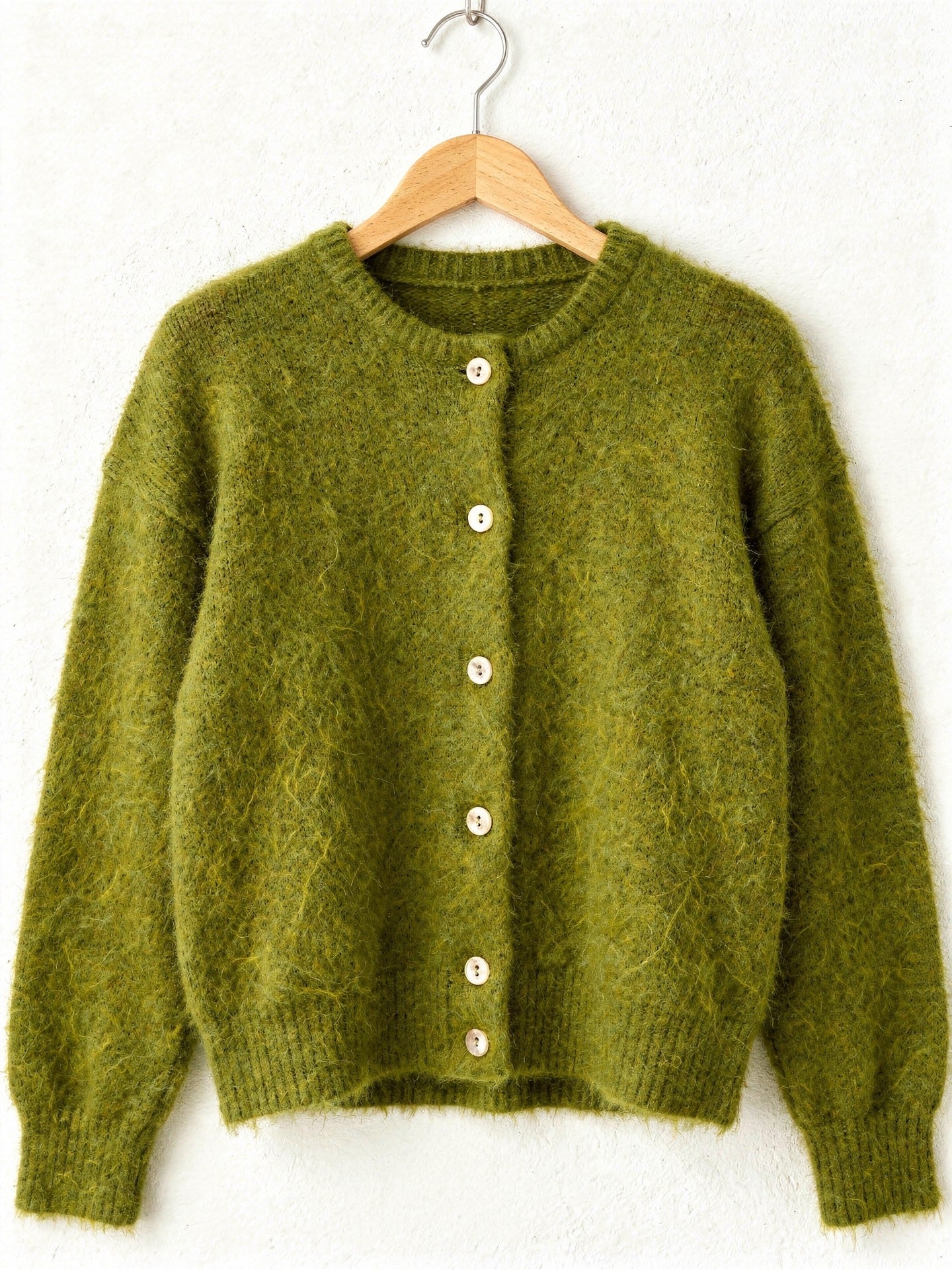 Moss green button-through cardigan in brushed knit on a wooden hanger