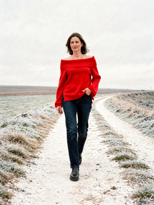 Off the shoulder jumper in Scarlet, worn with jeans on a chalk track