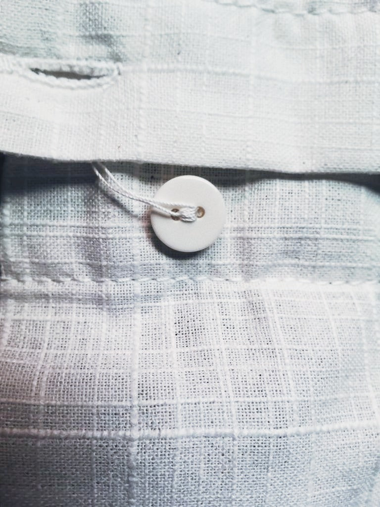 Close up of the textured slub weave and a flat white two hole button on the oversized shirt