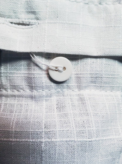 Close up of the textured slub weave and a flat white two hole button on the oversized shirt