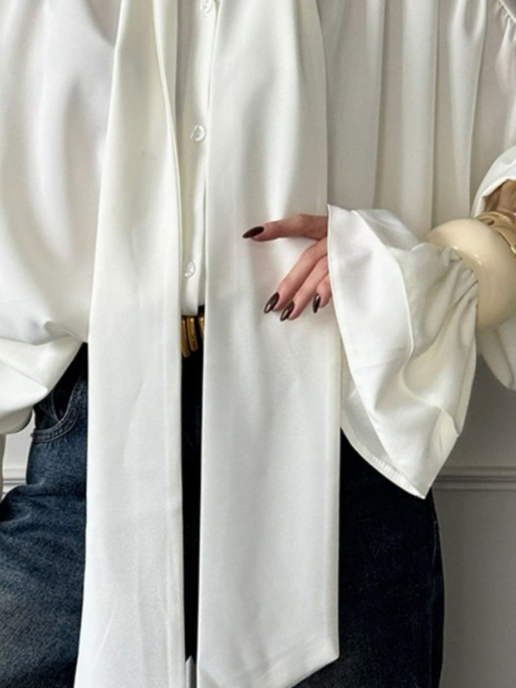 Oversized white satin blouse worn open with denim