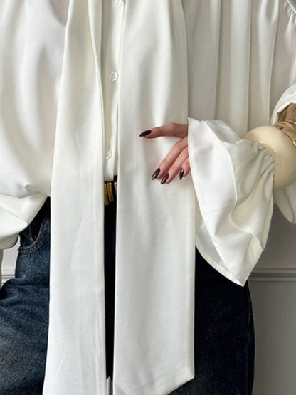 Oversized white satin blouse worn open with denim