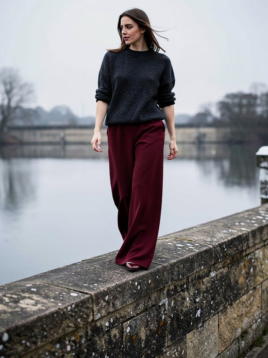 Woman walking in claret palazzo trousers with a pull on elasticated waist and a wide fluid leg
