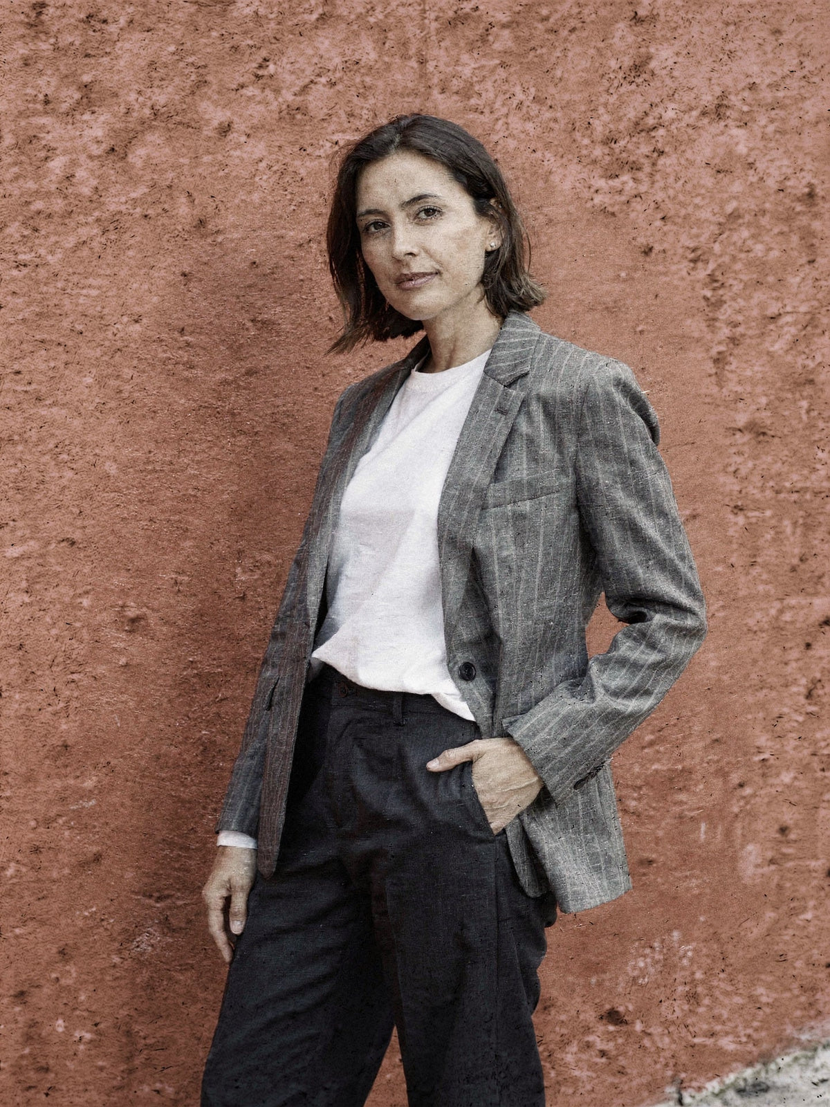 Pinstripe blazer worn with a hand in the pocket, close crop