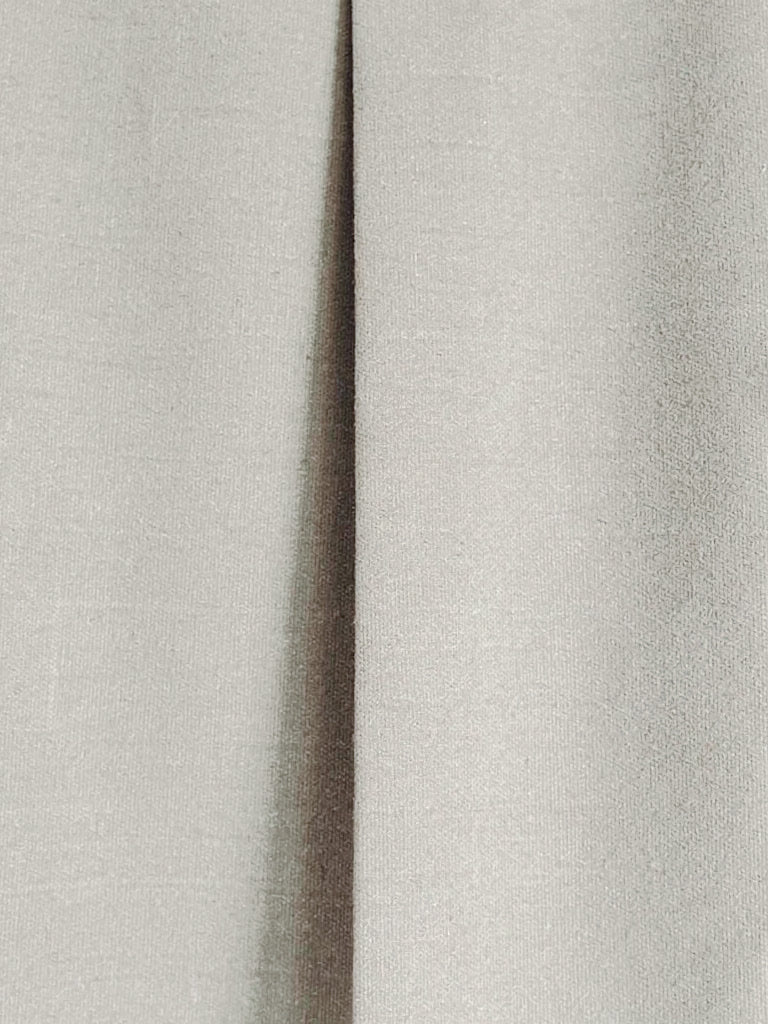 Close up of the matte woven cloth and a pressed box pleat on the midi skirt