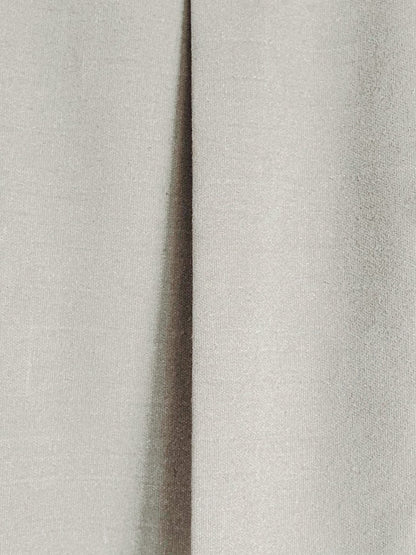 Close up of the matte woven cloth and a pressed box pleat on the midi skirt