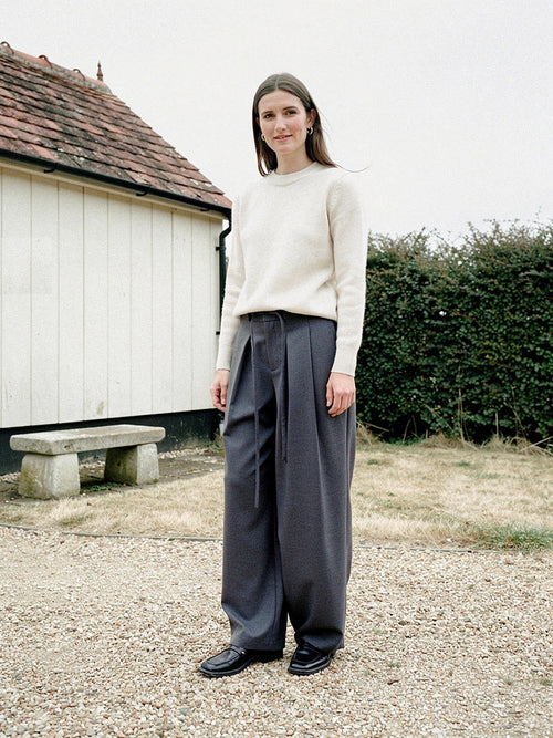 Slate grey pleated trousers with a barrel leg worn in a farm yard