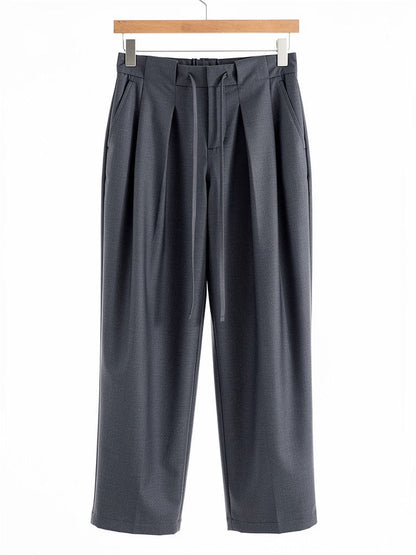 Slate grey pleated trousers on a hanger, front view