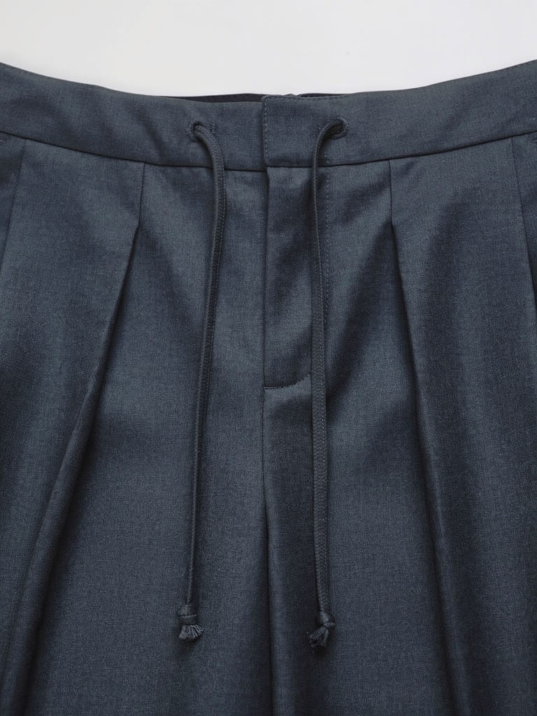 Waistband detail of pleated trousers with a self fabric drawstring