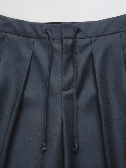 Waistband detail of pleated trousers with a self fabric drawstring