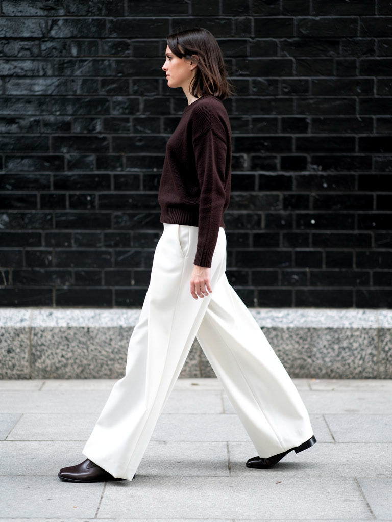 Pleated wide-leg trousers in paper white worn with a dark jumper