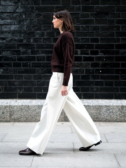 Pleated wide-leg trousers in paper white worn with a dark jumper