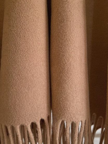 Close-up of the brushed double-faced cloth and the twisted cord fringing of the poncho cape
