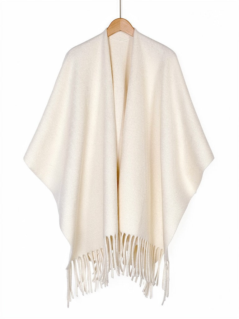 Open-front poncho cape in Muslin on a wooden hanger, showing the fringed hem