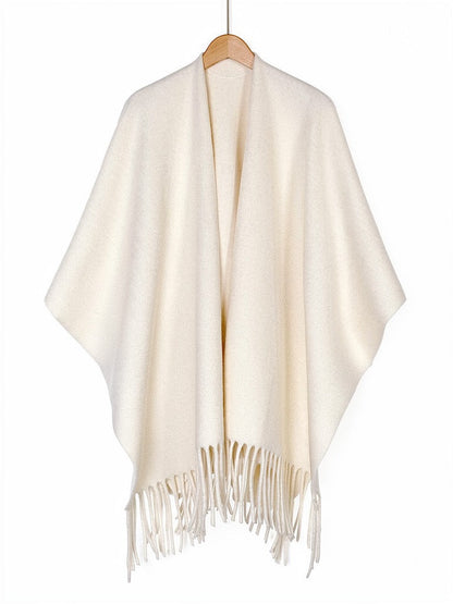 Open-front poncho cape in Muslin on a wooden hanger, showing the fringed hem