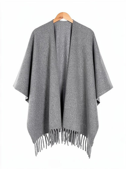 Open-front poncho cape in Smoke on a wooden hanger, showing the fringed hem