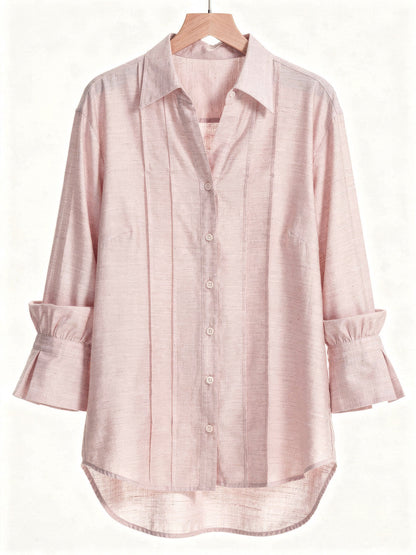 Powder pink blouse on a wooden hanger with a pintuck front and deep fluted cuffs