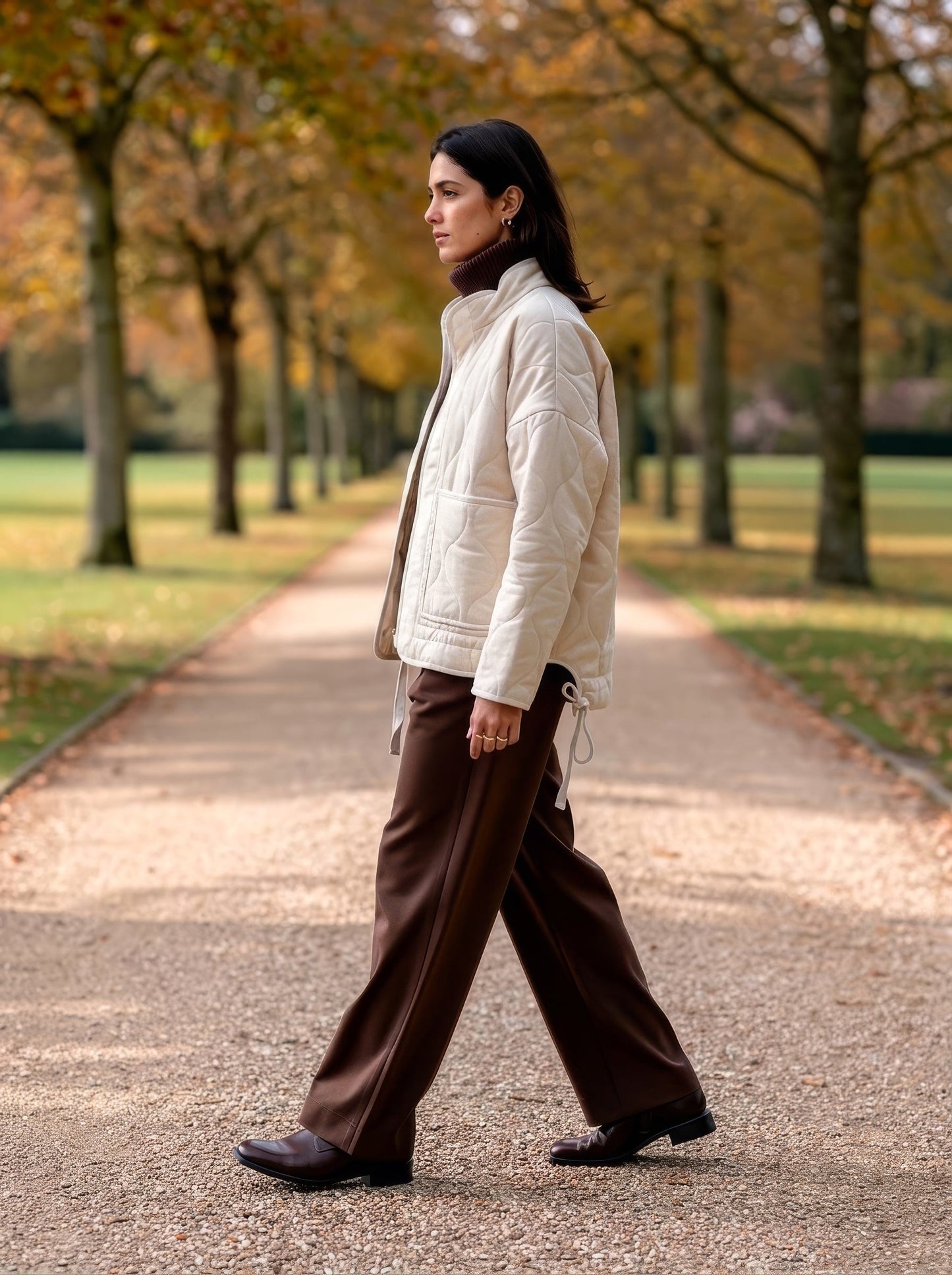 Ecru quilted jacket worn over a brown rollneck on an autumn beech avenue