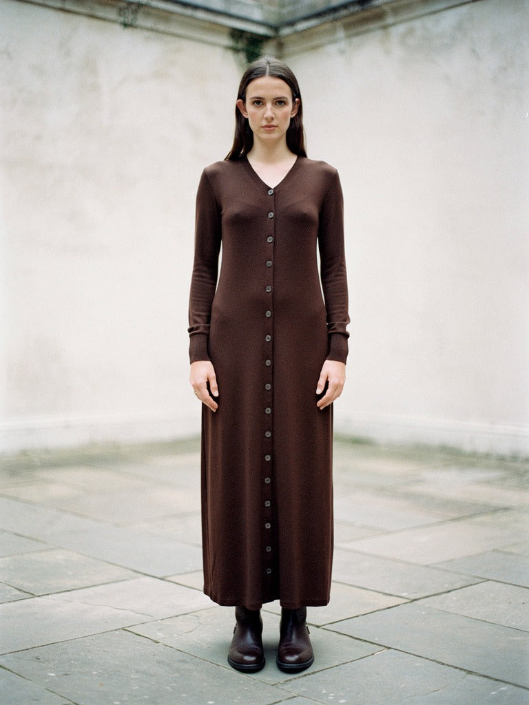 Ribbed maxi dress in Dark Chocolate worn in a walled court, front view, full length