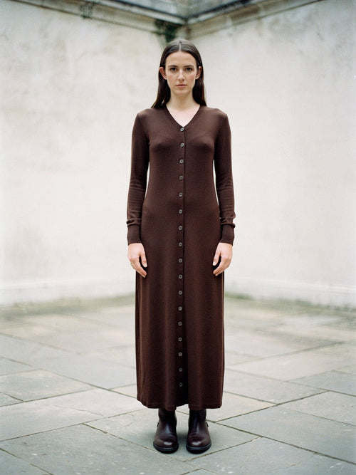 Ribbed maxi dress in Dark Chocolate worn in a walled court, front view, full length
