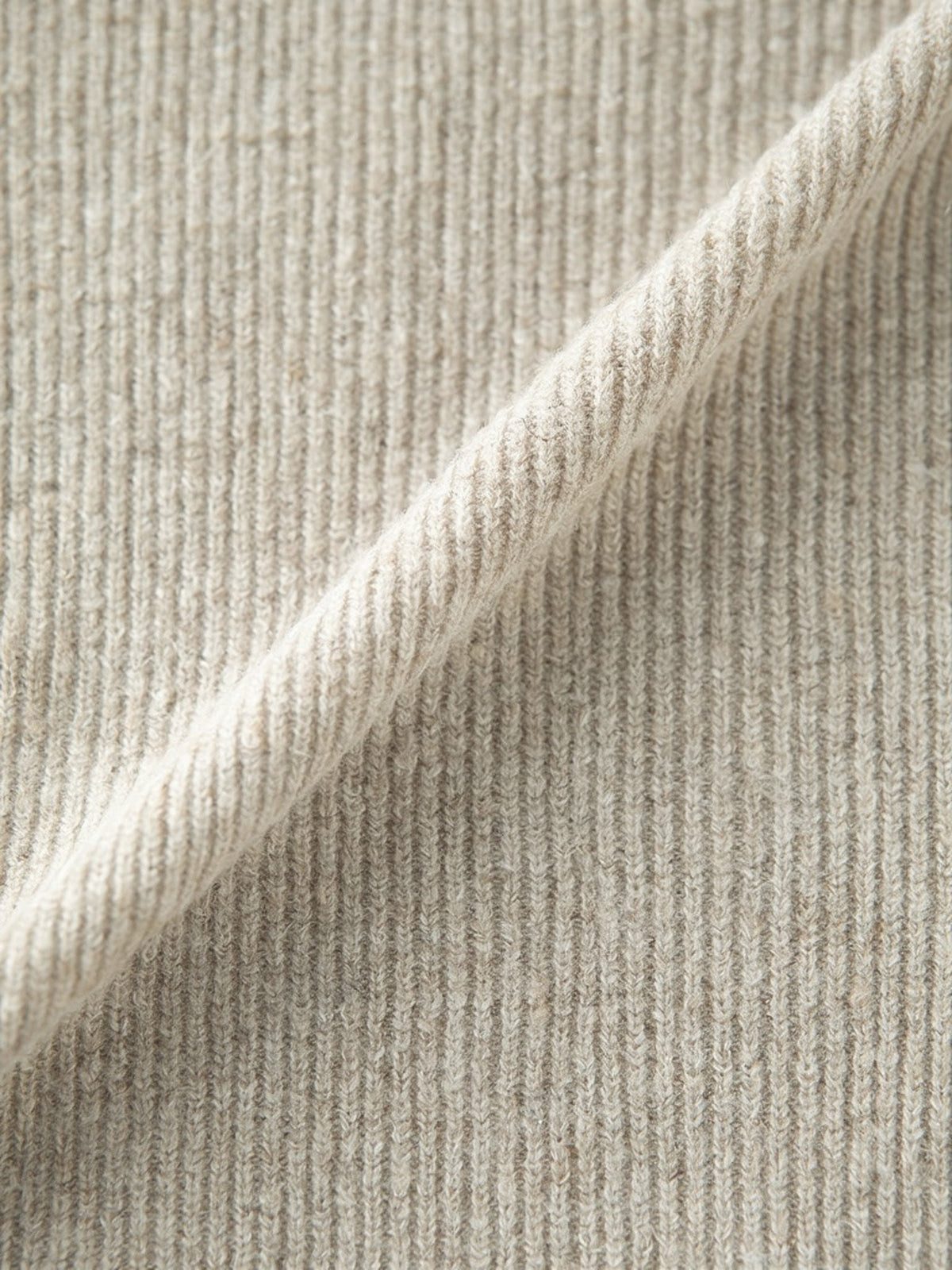 Close view of the fine vertical rib of the knitted skirt, matte with a soft brushed halo and a quiet oatmeal marl
