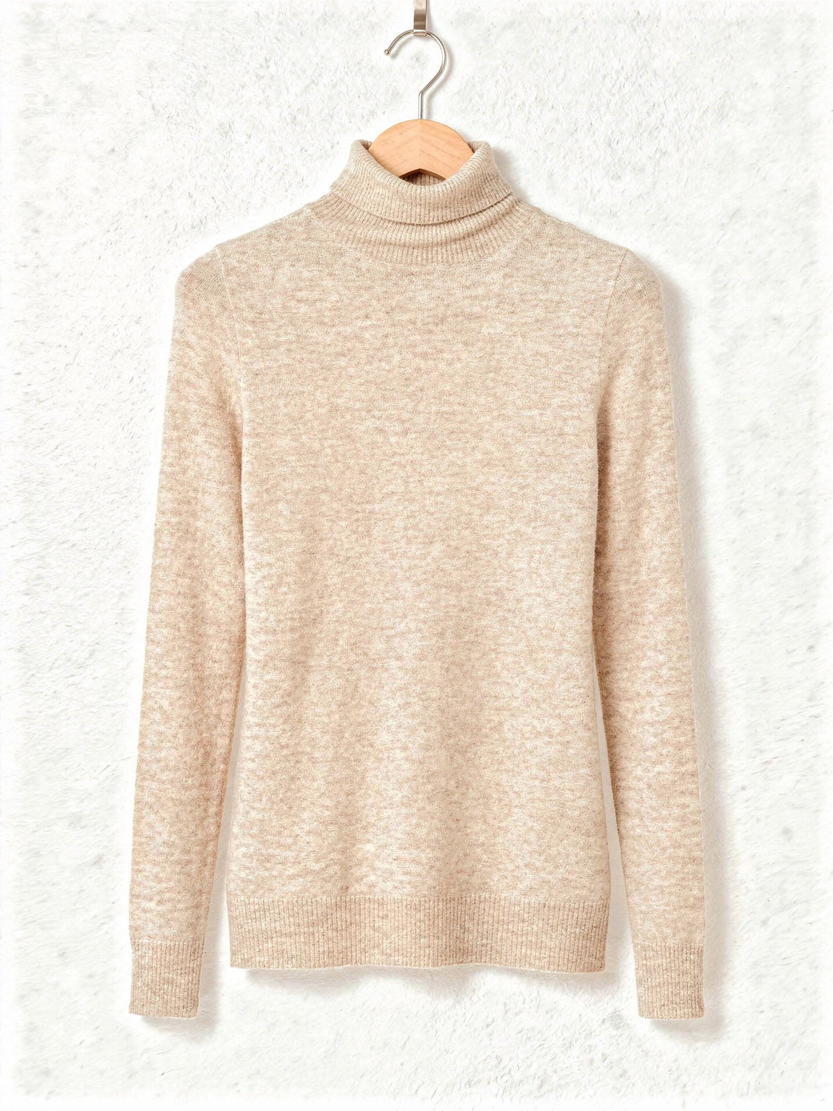 Roll neck jumper in Barley, a warm cream fine knit, on a wooden hanger