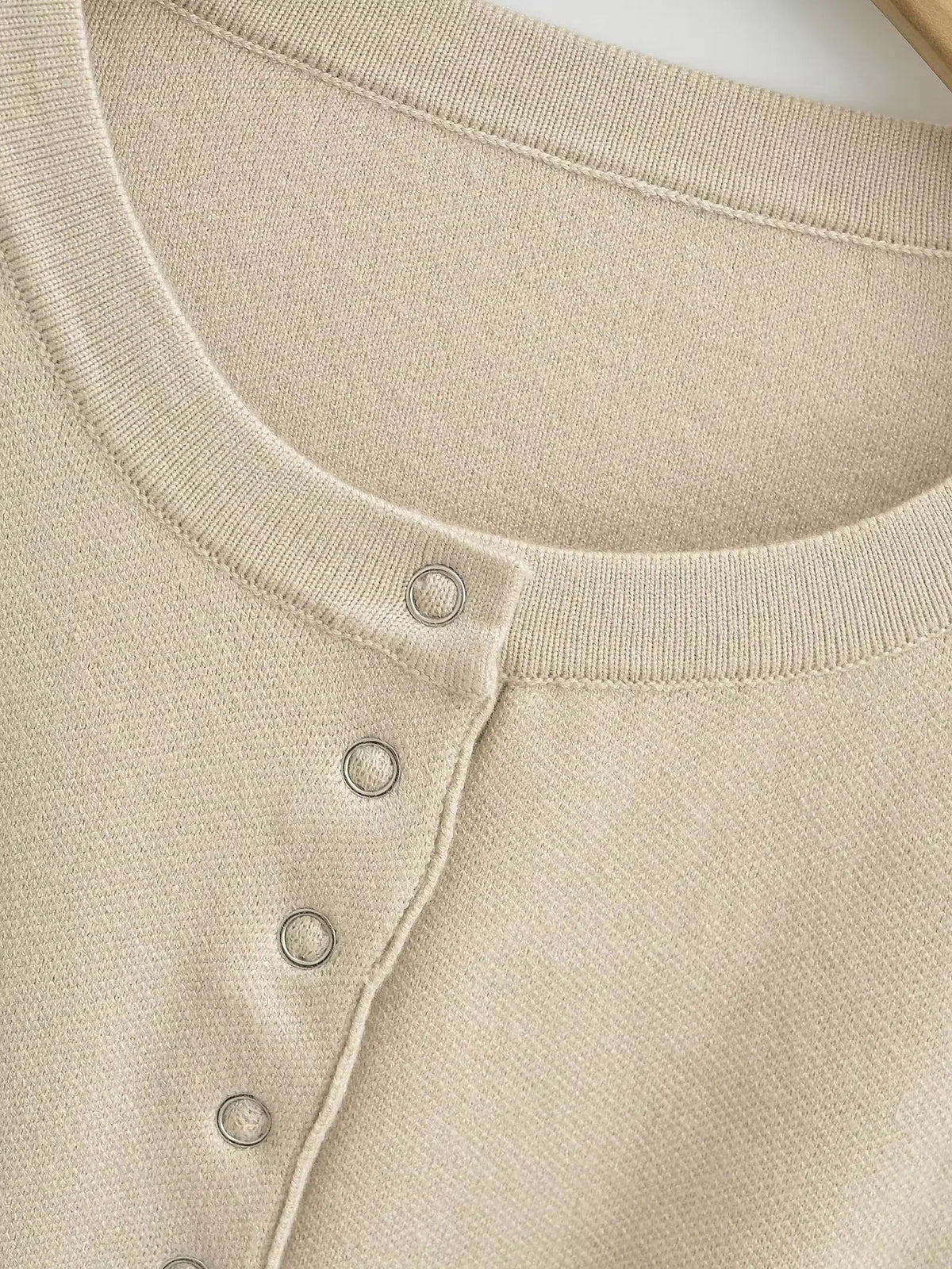 Close-up of the ribbed crew neckband and silver press studs on the cropped cardigan