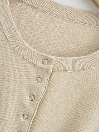 Close-up of the ribbed crew neckband and silver press studs on the cropped cardigan