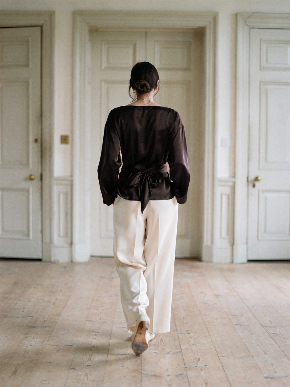 Back of the chocolate satin blouse with its sash tied in a bow at the waist