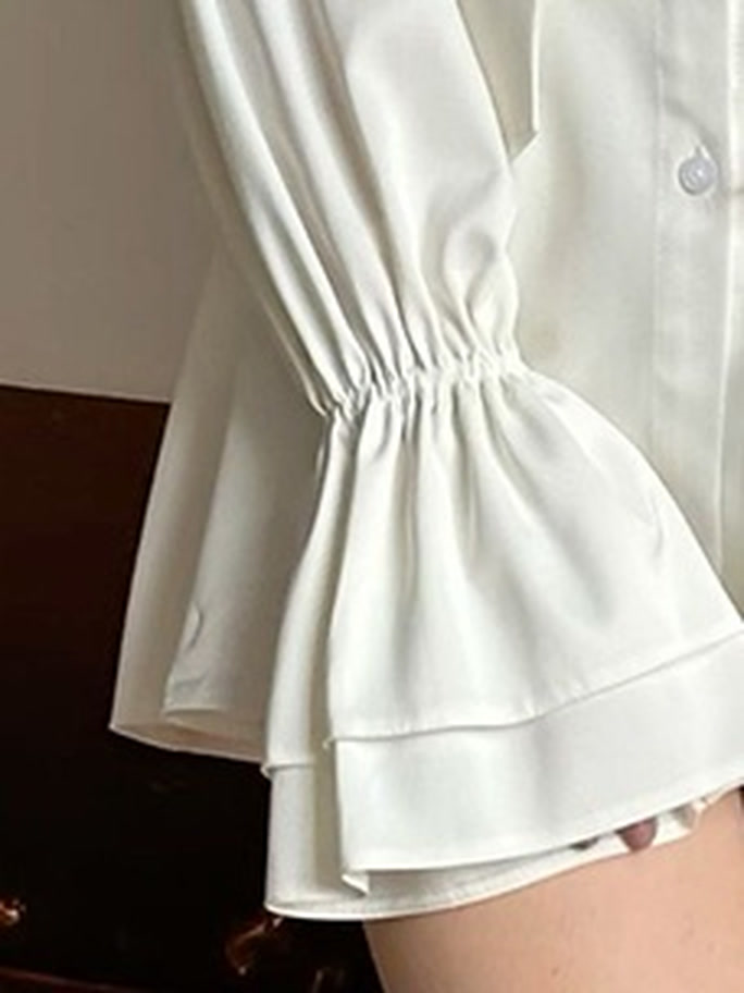 Tiered flounce cuff detail on a white satin puff sleeve blouse