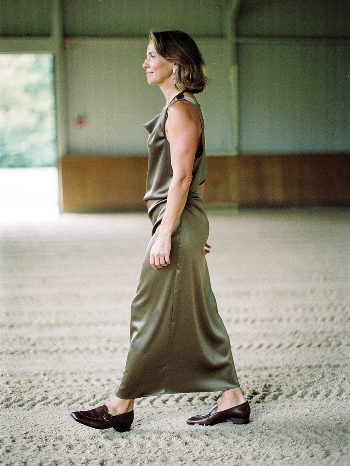 Woman walking in a Thyme olive satin maxi dress, side view, full length