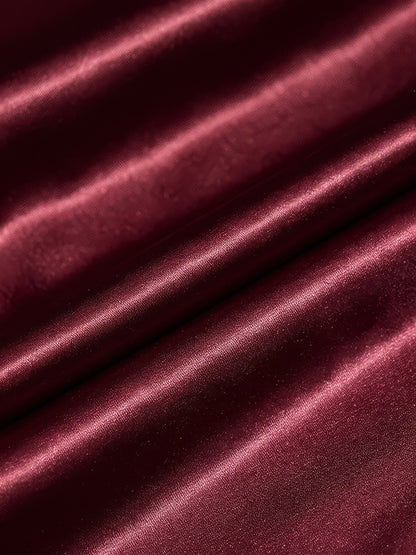 Close-up of the satin weave of the midi dress, showing the sheen along each fold