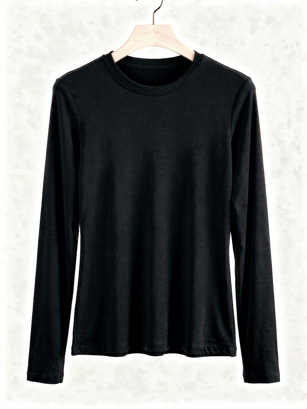 Black silk blend top with a ribbed crew neck and long sleeves, shown on a wooden hanger