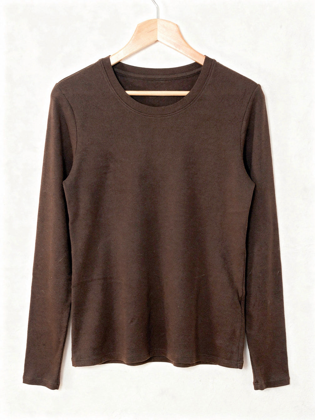 Chocolate silk blend top with a ribbed crew neck and long sleeves, shown on a wooden hanger