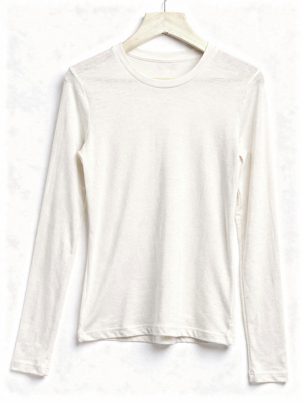 Cream silk blend top with a ribbed crew neck and long sleeves, shown on a wooden hanger