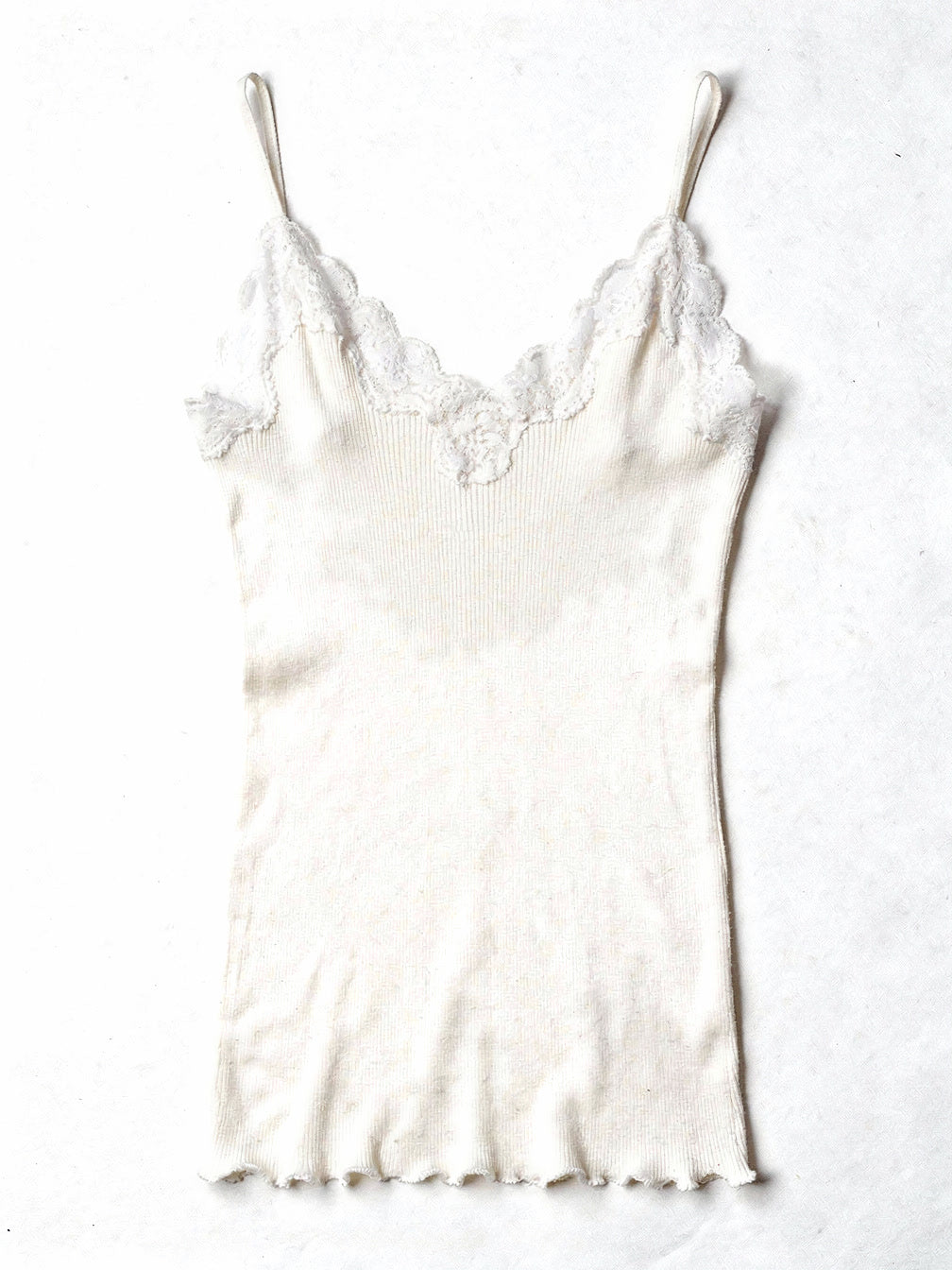 Milk white silk cami in a fine ribbed knit with lace trim, shown flat on white