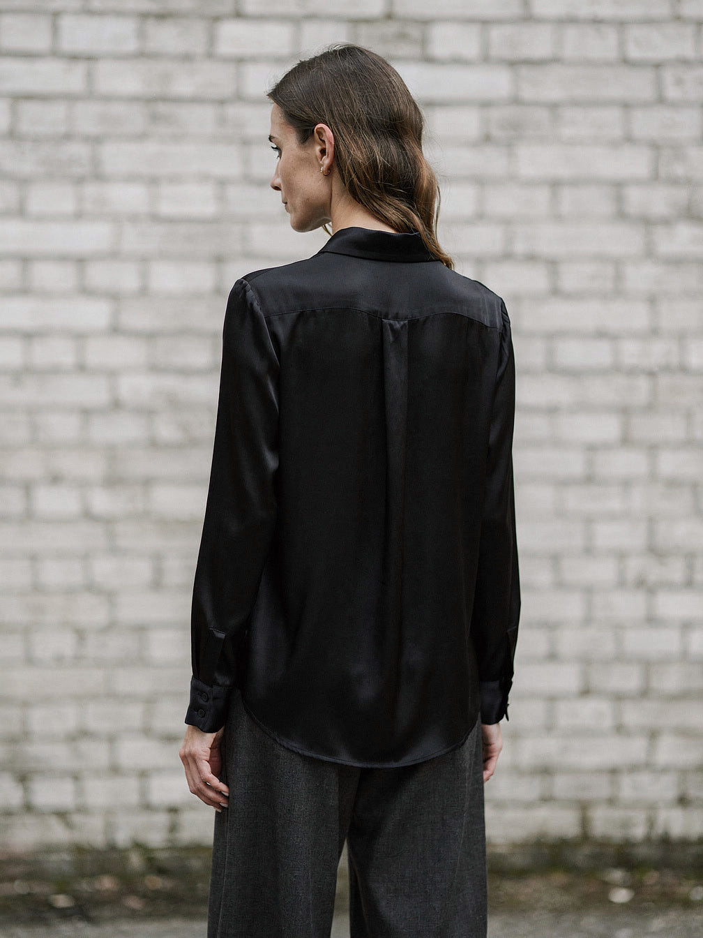 Back view of the black silk shirt showing the yoke seam and curved shirt tail hem