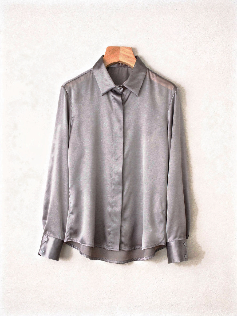 Pearl grey silk shirt on a wooden hanger showing the point collar and curved hem