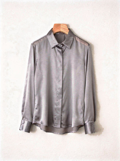 Pearl grey silk shirt on a wooden hanger showing the point collar and curved hem