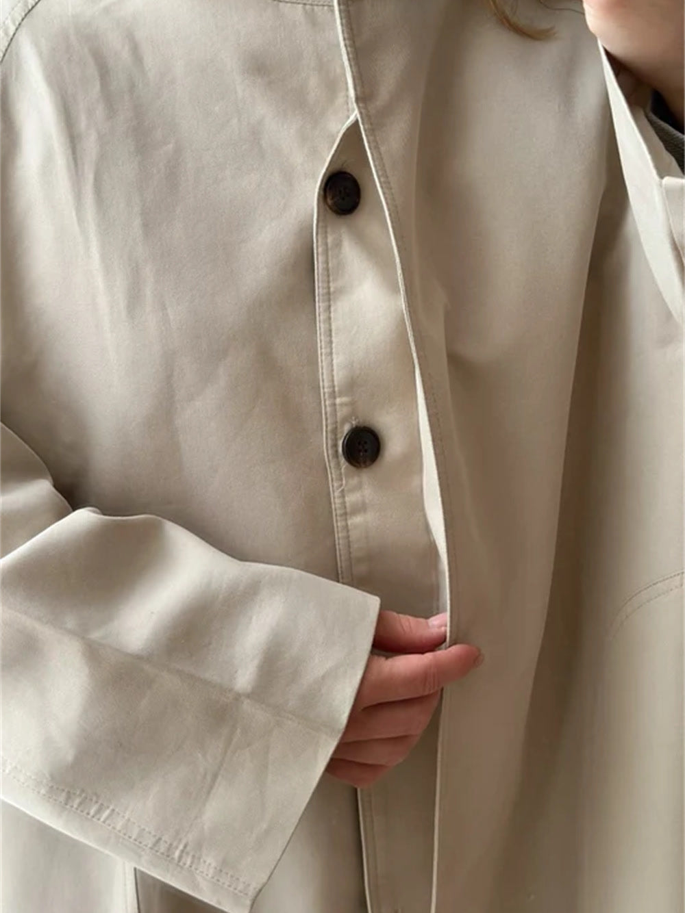 Detail of the standing band collar, the tonal buttons and the deep turn back cuff of the stand collar coat