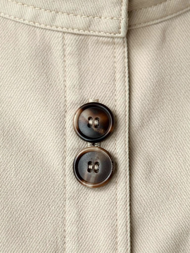 Close up of the matte cotton blend twill, the topstitched placket and the tonal four hole buttons