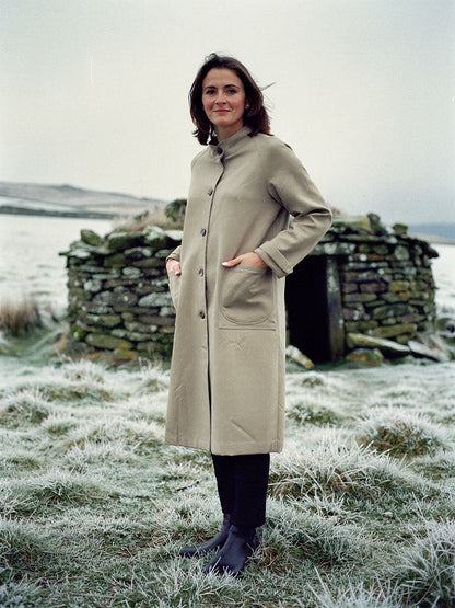 Womens stand collar coat in Sesame sand, oversized cotton blend twill, worn buttoned in a frosted upland pasture