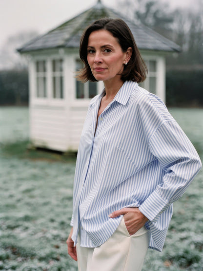 Woman wearing an oversized blue and white striped shirt with an open point collar